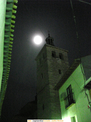 6 de Octubre de 2006. Vista de la Iglesia Parroquial un día de luna llena
Lástima que este fin de semana de luna llena no hayan iluminado la Iglesia. Las fotos nocturnas hubiesen sido mucho más espectaculares. Aún así por su interés publico la foto. Dicha foto ha podido salir (aunque no demasiado bien) por la existencia de dos fuentes de luz: una artificial (en la parte baja de la imágen, un foco de la calle) y otra natural, en la parte de arriba de la foto (la luna llena resplandeciente). Las fotos de la Iglesia y la luna son difíciles de conseguir porque hay que buscar horas específicas y ubicaciones específicas para ello (ello supone unos cuantos viajes para arriba y abajo por el pueblo).
A ver si por lo menos algún fin de semana de luna llena nos iluminan la Iglesia para hacerle un buen reportaje fotográfico. 
