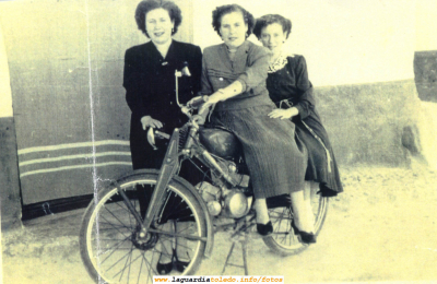 Tres mujeres posando con una moto. Años 50
