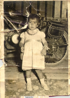 Niña posando delante de una moto. Años 60
