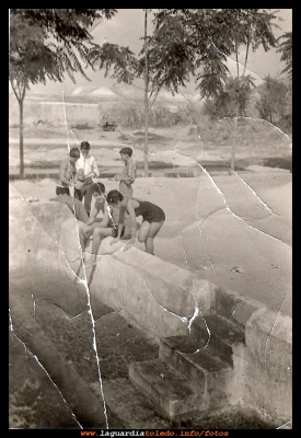 Bañistas en la 1ª piscina año 1967.
Año 1967, esta es la primera piscina que tuvimos en La Guardia, a partir de un baño que había para las mulas, y donde se echaban a remojar el esparto y los ataeros, para que se ablandasen.  Este se adecento con un suelo de cemento y las paredes pintadas de blanco, así consiguió el pueblo su piscina. 
Al principio solo se bañaban los hombres hasta que se atrevieron las chicas, que  solían ser  las que venían de Madrid a pasar las vacaciones al pueblo.
Palabras clave: Bañistas;1967;piscina