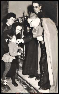 BESANDO EL ANILLO
Carmen Espada Huete con  6 años besa el anillo del obispo, ayudada por la tía Aurelia “la malaña”, por detrás esta Paca Pedraza. y al lado del obispo, don José Vicente González.  Año 1965
Palabras clave:  besa  anillo obispo