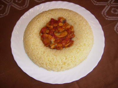 Arroz con champiñones
Arroz con Champiñón:
 Para 5 personas, ingredientes: Arroz ½  k, Azafrán, Aceite, Cebolla ¼ k, Queso rallado 50 g, Champiñones ½ k, Tomates maduros ½ k y sal.
Elaboración: Se pone a hervir agua, la mitad de la cebolla  se corta muy fina, y el resto en juliana. En un recipiente resistente al horno se rehoga  la cebolla cortada fina a fuego flojo, cuando este transparente se echara el arroz, y se le moja con el agua hirviendo, se echara unas hebras de azafrán y la sal. Se deja hervir 8 minutos y se mete  al horno caliente durante 12 minutos más, para que se termine de hacer. Al sacarlo se añade 50 g de queso rallado, se mueve todo con una cuchara para que se mezcle el queso y el arroz.
Salsa de Champiñón: en una sartén con aceite, se rehoga la cebolla que tenemos cortada en juliana, agregar el tomate picado y dejar unos 5 m, añadir el champiñón limpio y cuarteado, dejar cocer a medio fuego y tapado. Emplatar, con un molde de corona,  con la salsa en el centro.    

Palabras clave: Arroz con salsa de champiñon